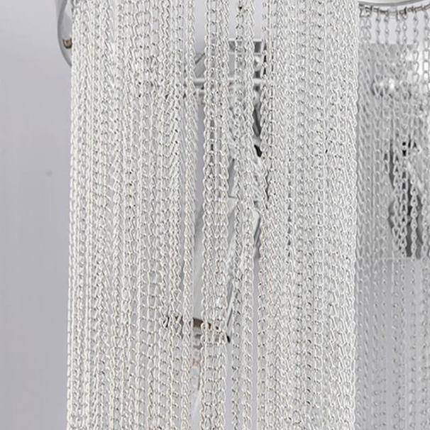 The Cadena chain tassel wall sconce by Morsale.com lit in a living room, modern stainless steel and aluminum.