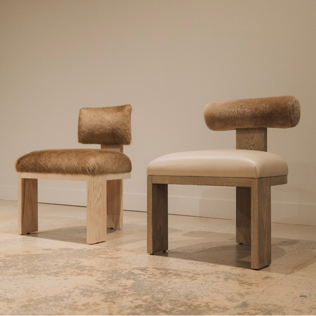 Two luxury dining chairs with wooden frames on a neutral background