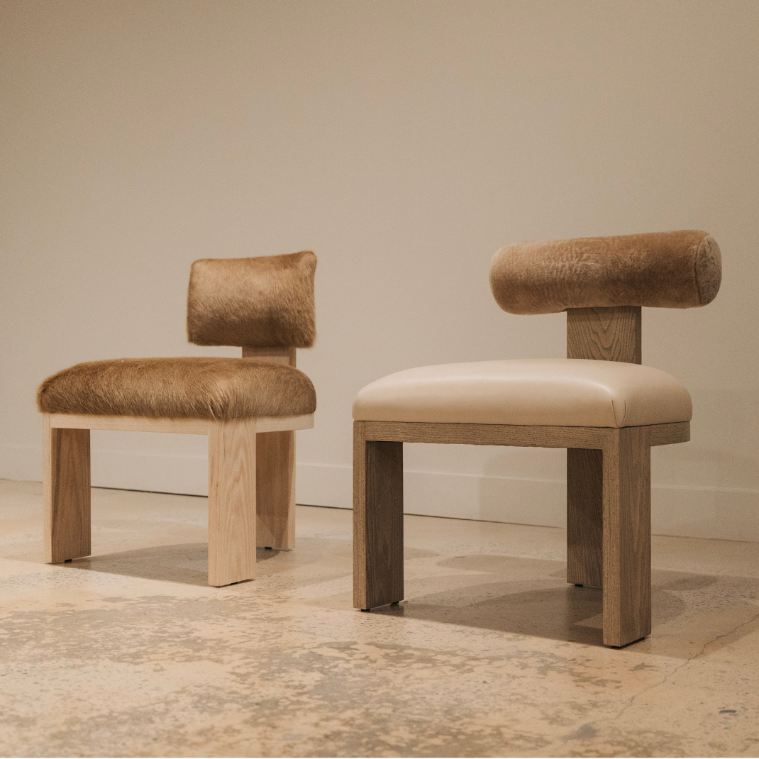 Two luxury dining chairs with wooden frames on a neutral background