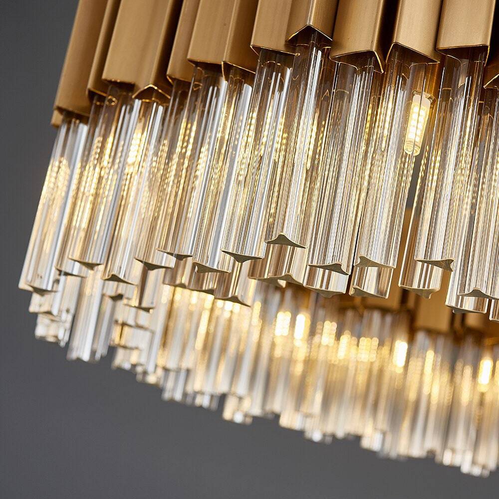 Close-up of the Milano Dining Chandelier by Morsale.com, featuring modern gold accents and elongated clear glass prisms, glowing warmly against a neutral background.
