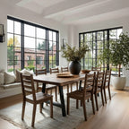 Dining room with wooden table and chairs, large windows, and indoor plants.