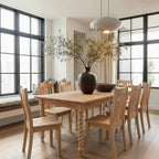Dining room with wooden table and chairs, large windows, and decorative vase.