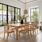 Dining room with wooden table and chairs in a bright room with large windows.