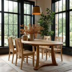 Dining room with wooden table and chairs near large windows.