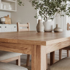 close up image of the corner of an oak dining table with matching chairs