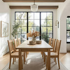Dining room with wooden table and chairs, large windows, and decorative elements.