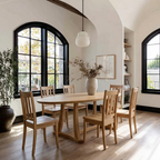 Dining room with wooden table and chairs near large windows.