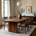 Dining room with wooden table and chairs, vase with flowers on the table.
