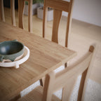 Wooden dining table with a green ceramic bowl and white tray.