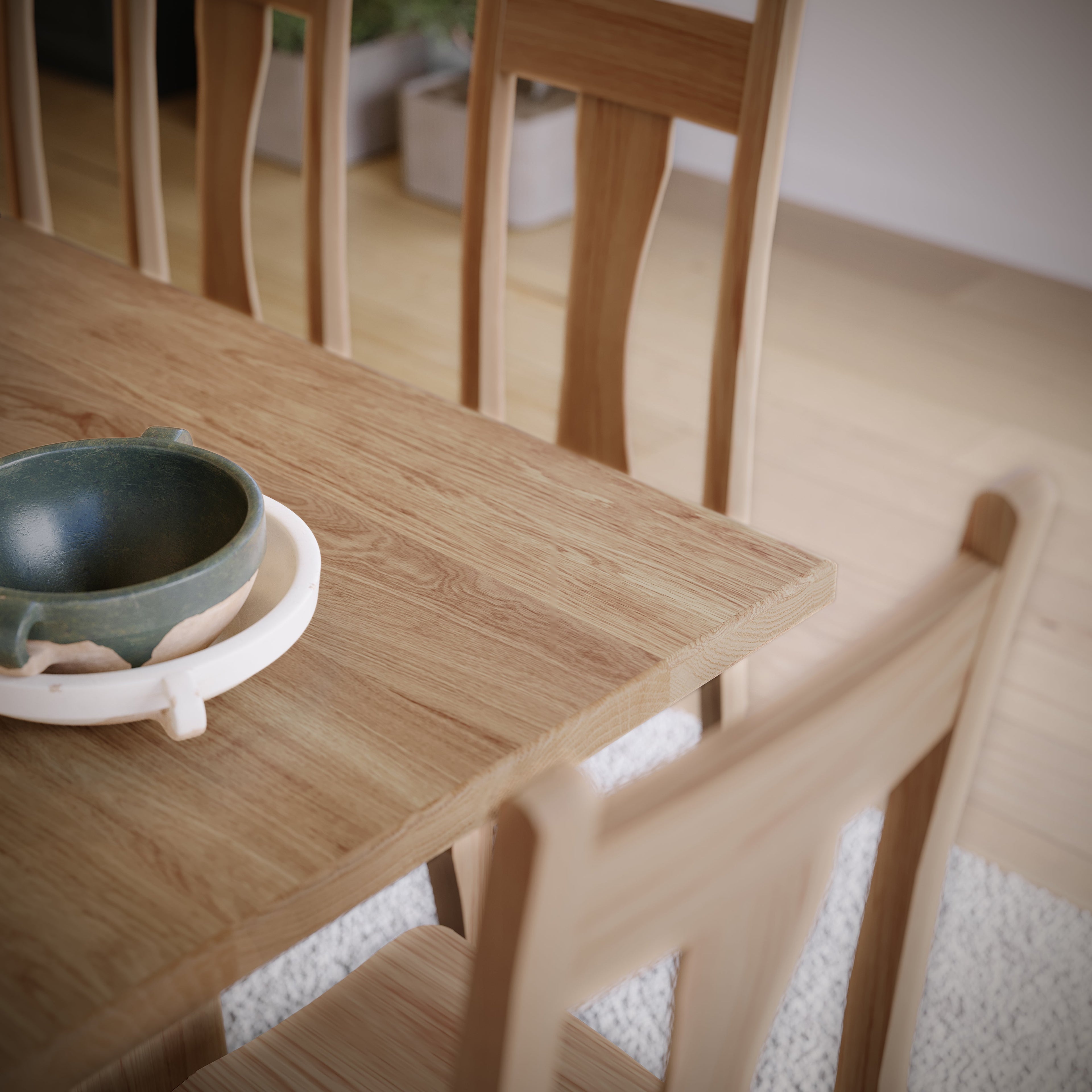 Wooden dining table with a green ceramic bowl and white tray.
