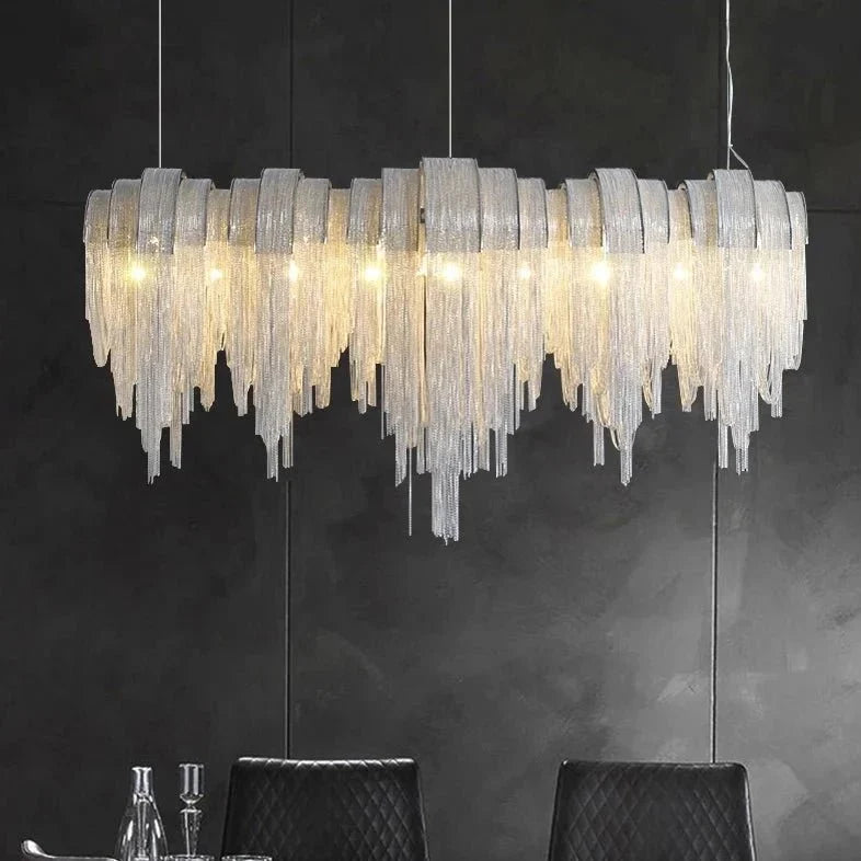 The Cadena 47-inch tassel dining chandelier from Morsale.com casting warm light, polished steel frame with aluminum tassels.