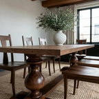 Dining room with wooden table and chairs, featuring a vase with greenery.