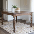A rectangular dining table with a straight edge, featuring a wood finish and metal legs, placed on a patterned rug.