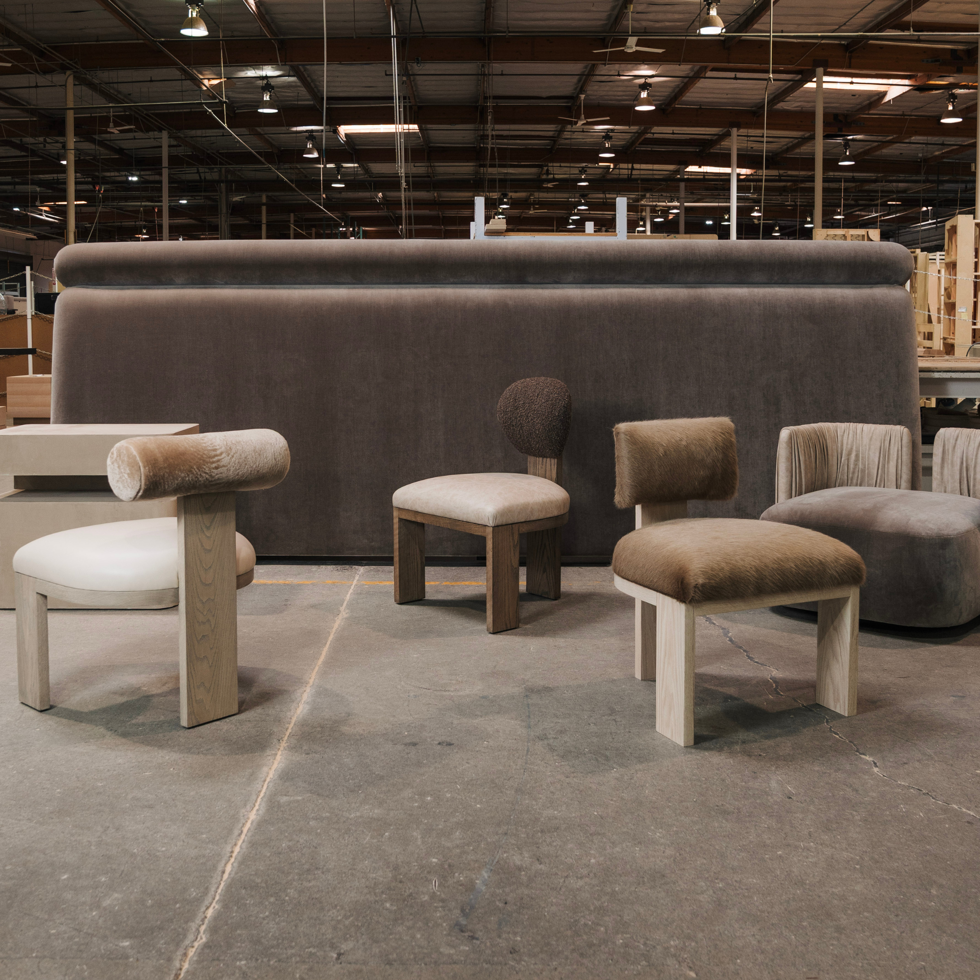 Modern furniture including chairs and ottomans in a warehouse setting