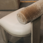 Close-up of a dining chair with a Cylindrical bolster backrest and leather seat.
